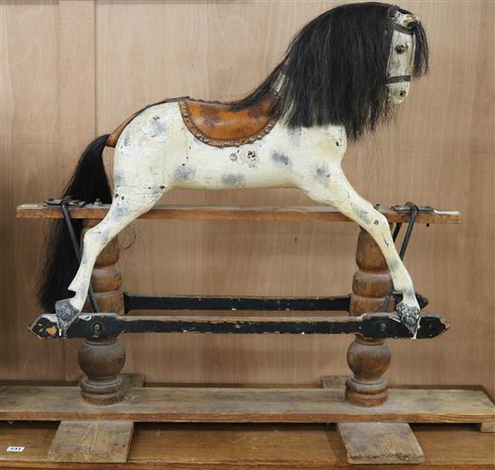 A Victorian painted carved wood rocking horse, with brass studded leather saddle, in trestle frame H.87cm